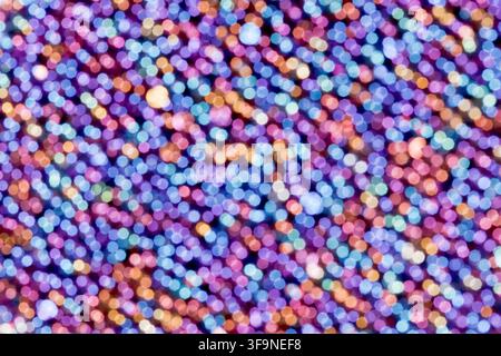 Out of focus lights form overlapping round bokeh dots in violet, blue and warm orange tones, creating a full frame abstract texture with a festive glo Stock Photo