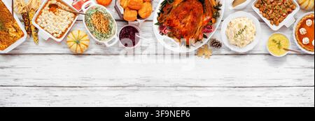 Traditional Thanksgiving turkey dinner. Overhead view top border on a rustic white wood banner background. Turkey, mashed potatoes, stuffing, pumpkin Stock Photo