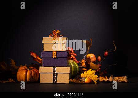 Stacked gift boxes with pumpkins berries and autumn foliage on dark background for Halloween Thanksgiving sale or seasonal advertising Stock Photo