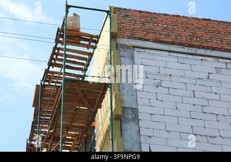 A fragment of brickwork in a new home with walls made of foam blocks. Construction site and insulation sheathing. Construction and scaffolding for she Stock Photo