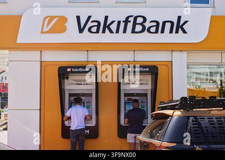 People back view standing and using VakifBank street ATM cash machines on a sunny day in the resort town of Marmaris, Muğla, Turkey. Stock Photo