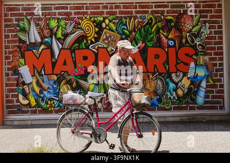 People walking past colourful graffiti street art with Marmaris sign painted on a brick wall background in resort town Marmaris, Turkey Stock Photo