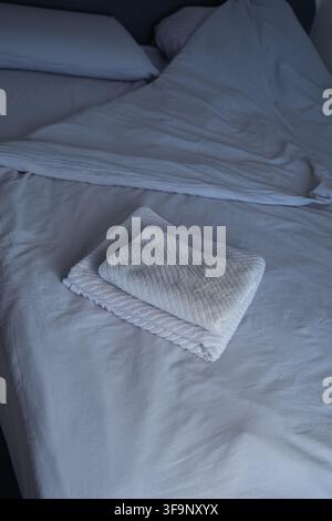 A close-up view from above of folded gray terry towels with a relief pattern lying on gray bedding Stock Photo