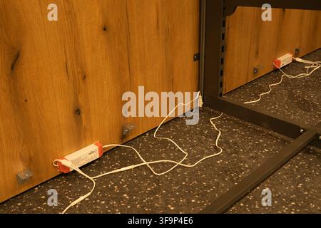 LED Drivers and White Electrical Cables Installed Behind Commercial Wooden Furniture Panel Structure on Speckled Floor Stock Photo