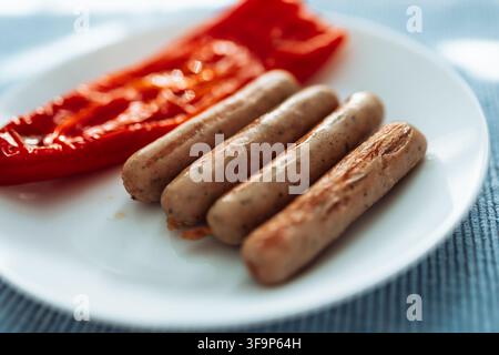 Grilled sausages with roasted red bell pepper on white plate Stock Photo