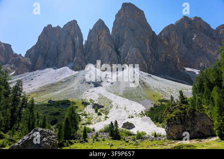 Towering dolomite peaks and pale limestone slopes rising above an alpine forest landscape in northern italy Stock Photo