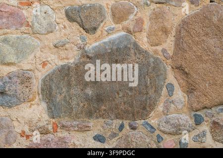 Textured stone wall featuring various sizes and colors of stones, showcasing natural materials and craftsmanship in a rustic setting Stock Photo