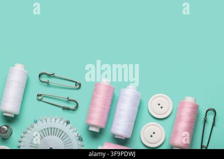 Composition with thread spools, ball pins and buttons on mint background, closeup Stock Photo
