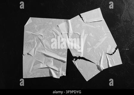 Two torn and crumpled white paper sheets glued to a dark textured wall, abstract urban background with copy space, this abstract urban background feat Stock Photo