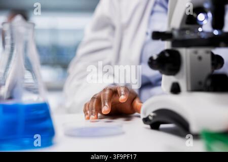 Close up of cytotechnologist inspecting new drug compound under microscope lens. Quality control analyst verifying medication quality and purity standards with optical device Stock Photo