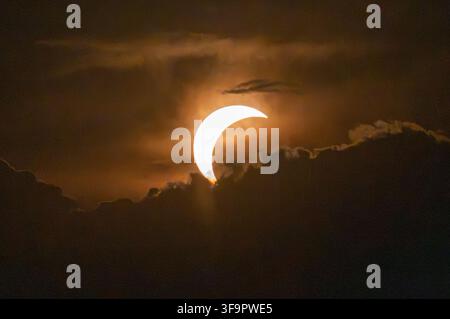 Aerial view of a partial solar eclipse partially obscured by dark clouds in the sky over Lugano, Ticino, Switzerland. Stock Photo