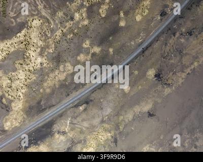 Aerial view of a lonely road cutting through the vast volcanic landscape of Iceland. Stock Photo