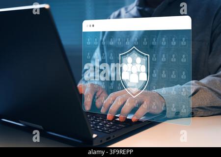 Close-up of a business user working on a laptop with shield and employee icons, symbolizing HR data protection, workforce privacy, access control, ide Stock Photo