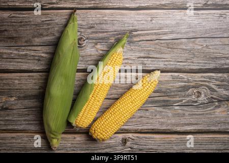 Fresh corn cobs on flat wooden background. Stock Photo