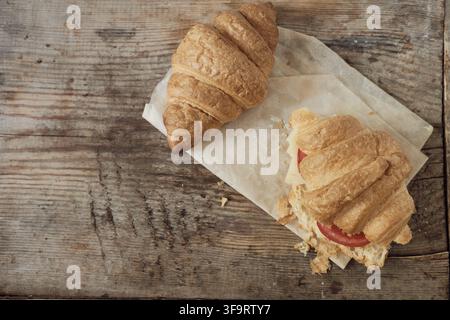 Morning breakfast of croissants. Two croissants on a wooden background. Hearty croissant with tomato and cheese. Close-up with a copy space for the te Stock Photo