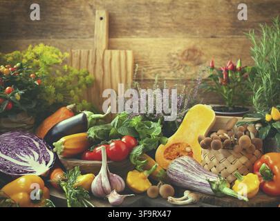 Assorted seasonal vegetables and fresh herbs on a rustic wooden table Stock Photo