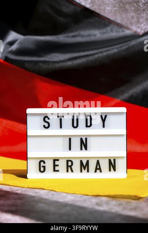 Lightbox with text STUDY IN GERMAN National symbol of Germany. German wave silky flag background. Concept of education and learning Stock Photo