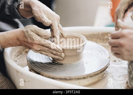The woman sculpts from clay. modeling on a potters wheel. Hands are molded from clay. Creative workshop. The girl sculpts from clay. Working atmospher Stock Photo