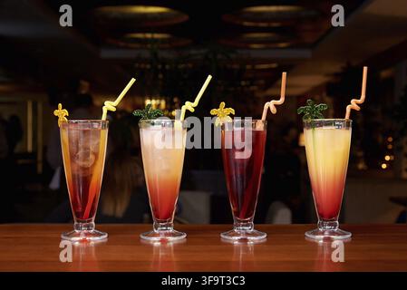 Row of different cocktails with straws on a dark background Stock Photo