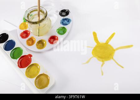 Kids painting concept - a drawing, watercolor palletes and a paint brush, isolated on a white background Stock Photo