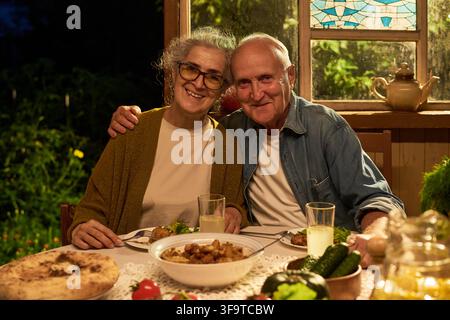 Portrait of Happy Senior Couple Having Dinner in Garden Stock Photo