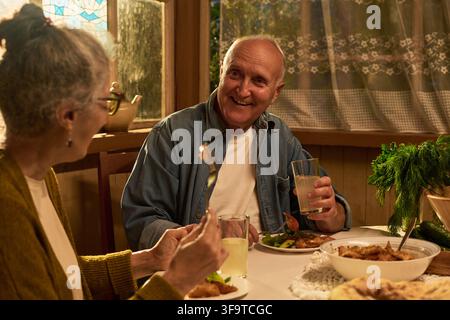 Happy Senior Couple Having Dinner and Talking at Home Stock Photo
