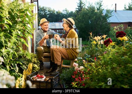 Happy Senior Couple Drinking Coffee in Beautiful Garden Stock Photo