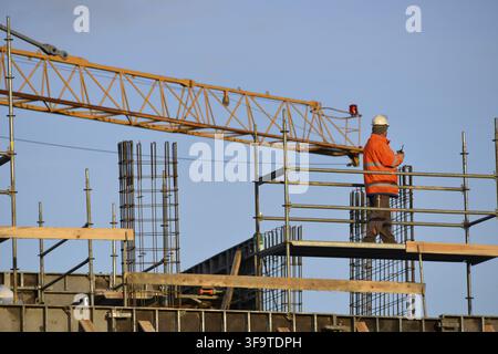 Construction site male builder worker wearing orange reflective vest and hard hat on scaffolfing in Gdansk, Poland, Europe, EU Stock Photo