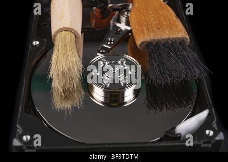 Cleaning the hard disk with a brush. Vacuuming old disk data on your computer. Dark background Stock Photo