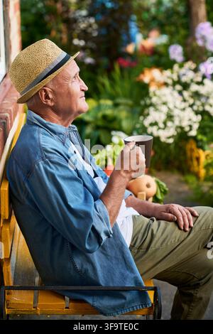 Senior Man Drinking Coffee on Bench in Garden Stock Photo