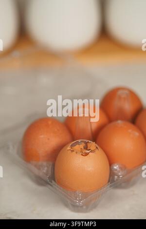 broken eggs are placed in a clear carton on the kitchen counter Stock Photo