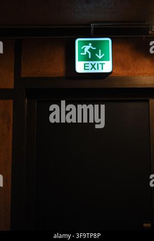 Exit sign above a dark door in a public building Stock Photo
