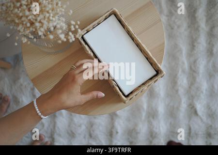 Hand reaching for a tissue paper in a box on a wooden table Stock Photo
