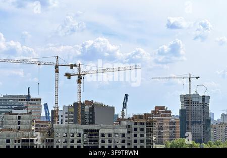 Urban Development: Tower Cranes Constructing Modern High-Rise Buildings Against Cloudy Skyline Stock Photo