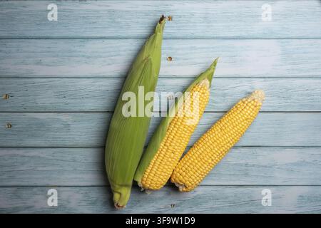 Fresh corn cobs on flat wooden background. Stock Photo