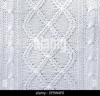 Wool sweater texture of white color with cable knitting stitch pattern and heart-shaped textile patch. Natural knitted wool white material with orname Stock Photo