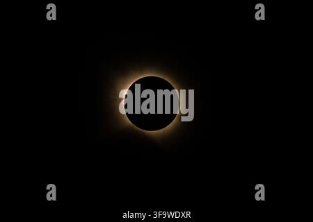 A stunning telephoto photograph capturing the dramatic moment of total solar eclipse. The black lunar disk is surrounded by the bright solar corona, w Stock Photo