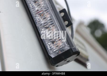 A led light bar mounted on white vehicle, close up detail with clear lens and black metal bracket Stock Photo