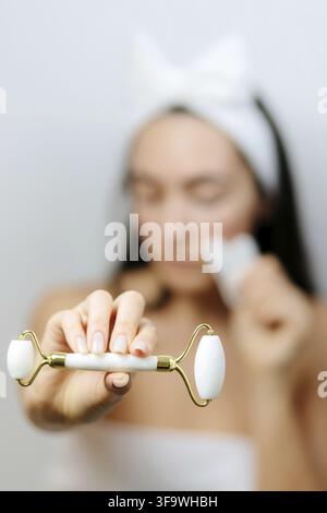 Jade Face Lifting Gouache Scraper Massager. Beautiful caucasian Woman Using face roller and scraper over skin. beauty face skin care at home Stock Photo