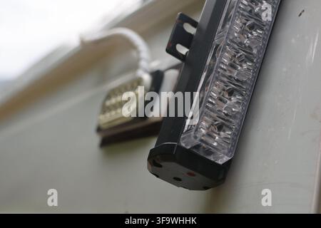 A led warning light bar mounted on white vehicle surface, with clear lenses and black housing creating close up automotive safety detail Stock Photo