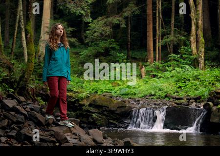 hiking travel concept of young curly hair woman portrait wearing touristic clothes in forest fresh natural environment space Stock Photo