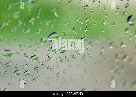 A water droplet on glass with green blurred background, creating fresh abstract texture and calm atmosphere after rainfall Stock Photo