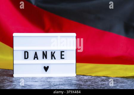 Lightbox with text DANKE THANK YOU National symbol of Germany. German wave silky flag background. Concept of thanksgiving day and gratitude Stock Photo