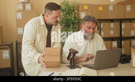 Two men scan and pack a cardboard box with hands visible, one holds a barcode scanner while the other places the parcel on a desk in a building; focus Stock Photo