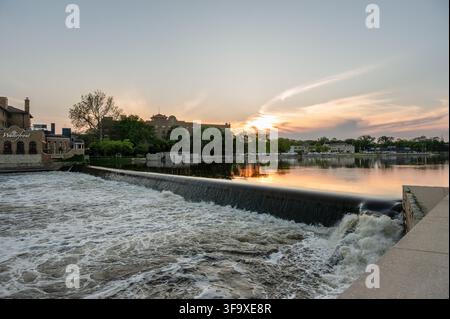 Water cascades over a Fox River dam at sunset Stock Photo