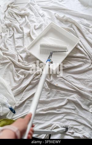 First person view holding a paint roller and tray Stock Photo