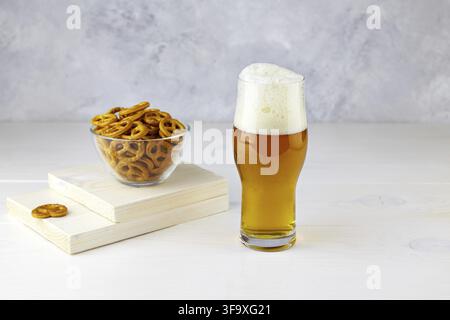 A glass of light beer with pretzels on a white wooden background. Stock Photo