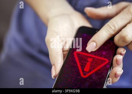 Mobile phone in female hands with screen showing compromised virus infected device. Cyber attack. Data breach concept Stock Photo