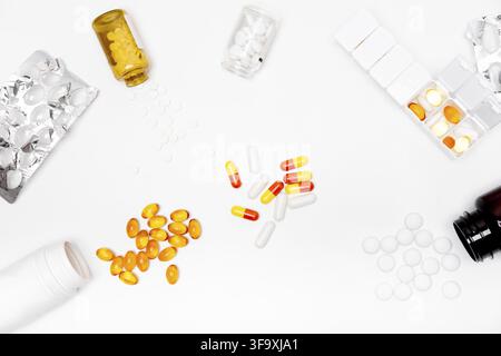 Pillbox by days of the week with fish oil and various pills, capsules and jars scattered on a white background, top view Stock Photo