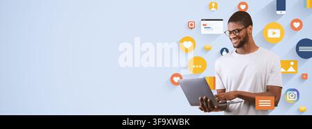 Smiling Young African American Man Using Laptop In Office, Technology And Business Concept Stock Photo